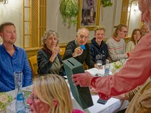 Verschiedene grüne Mitglieder sitzen an einem Tisch während eine Box für die Wahl der Delegierten durchgeht.