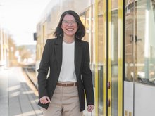 Thuy Nga Trinh läuft neben einer Bahn und lächelt in die Kamera