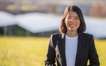 Thuy Nga Trinh steht vor einer Solaranlage