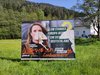 Zerstörtes Plakat in der Natur mit Haus dahinter